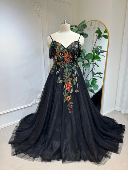 Black tulle wedding dress with vibrant floral embroidery, sweetheart corset bodice, spaghetti straps, and A-line skirt.