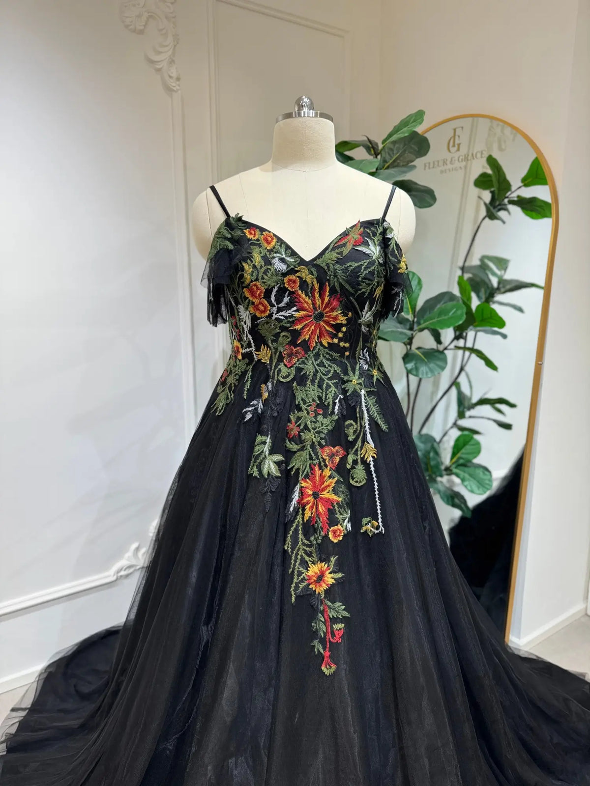 Black tulle wedding dress with vibrant floral embroidery, sweetheart corset bodice, and delicate spaghetti straps.