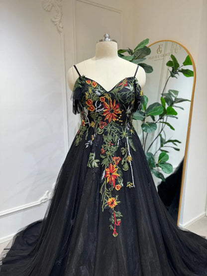 Black tulle wedding dress with vibrant floral embroidery, sweetheart corset bodice, and delicate spaghetti straps.