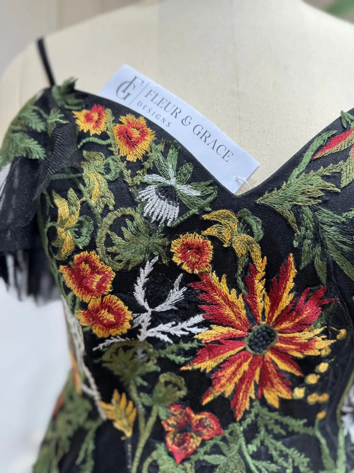 Black wedding dress featuring intricate, vibrant autumn floral embroidery on a structured sweetheart corset bodice.