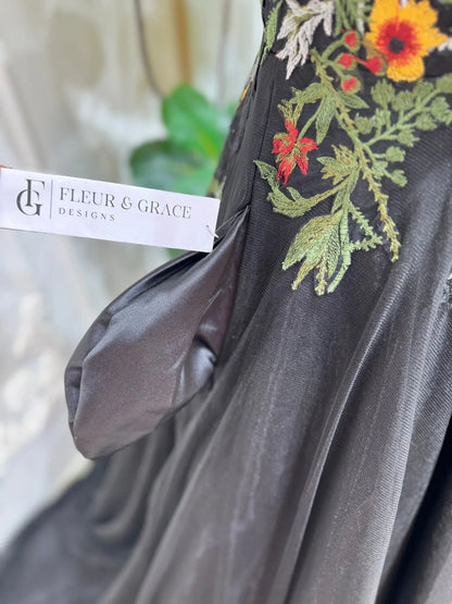 Black tulle wedding dress featuring vibrant floral embroidery, a structured corset bodice, and elegant off-shoulder sleeves.