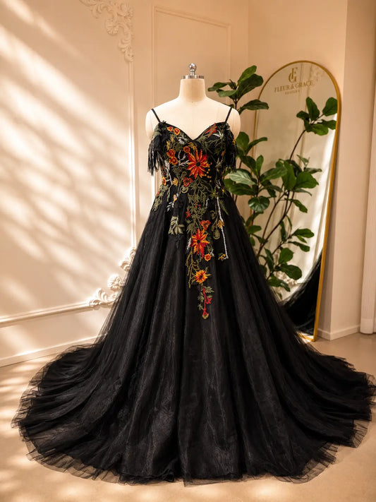 Black tulle wedding dress with vibrant floral embroidery, sweetheart corset bodice, spaghetti straps, and elegant A-line skirt.