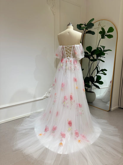 Pink tulle wedding gown with 3D floral appliqués, off-shoulder sleeves, lace-up back, and chapel-length train.
