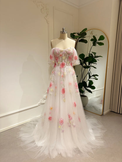 Pink tulle wedding gown with 3D floral appliqués, off-shoulder sleeves, sweetheart neckline, and chapel-length train.