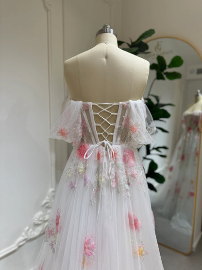 Luna Gown in white tulle with pink 3D floral appliqués, off-shoulder flutter sleeves, and a lace-up corset back.