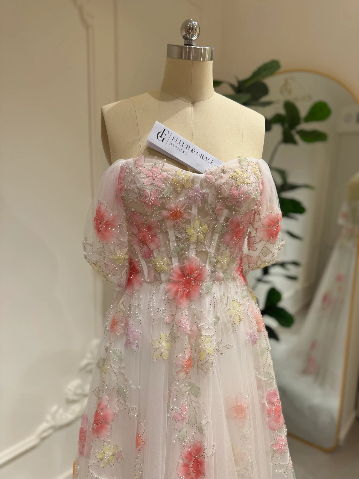Pink tulle wedding gown with off-shoulder sleeves, sweetheart neckline, and handmade 3D floral embroidery.