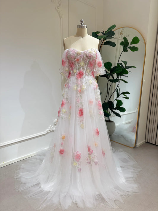 Pink tulle wedding gown with 3D floral appliqués, off-shoulder sleeves, sweetheart neckline, and chapel-length train.
