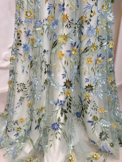 Meadow green tulle wedding dress featuring intricate blue, yellow, and green floral embroidery in an A-line silhouette.