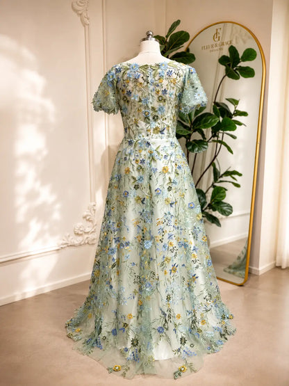 Meadow green A-line wedding dress with puff sleeves and intricate blue and yellow floral tulle embroidery.
