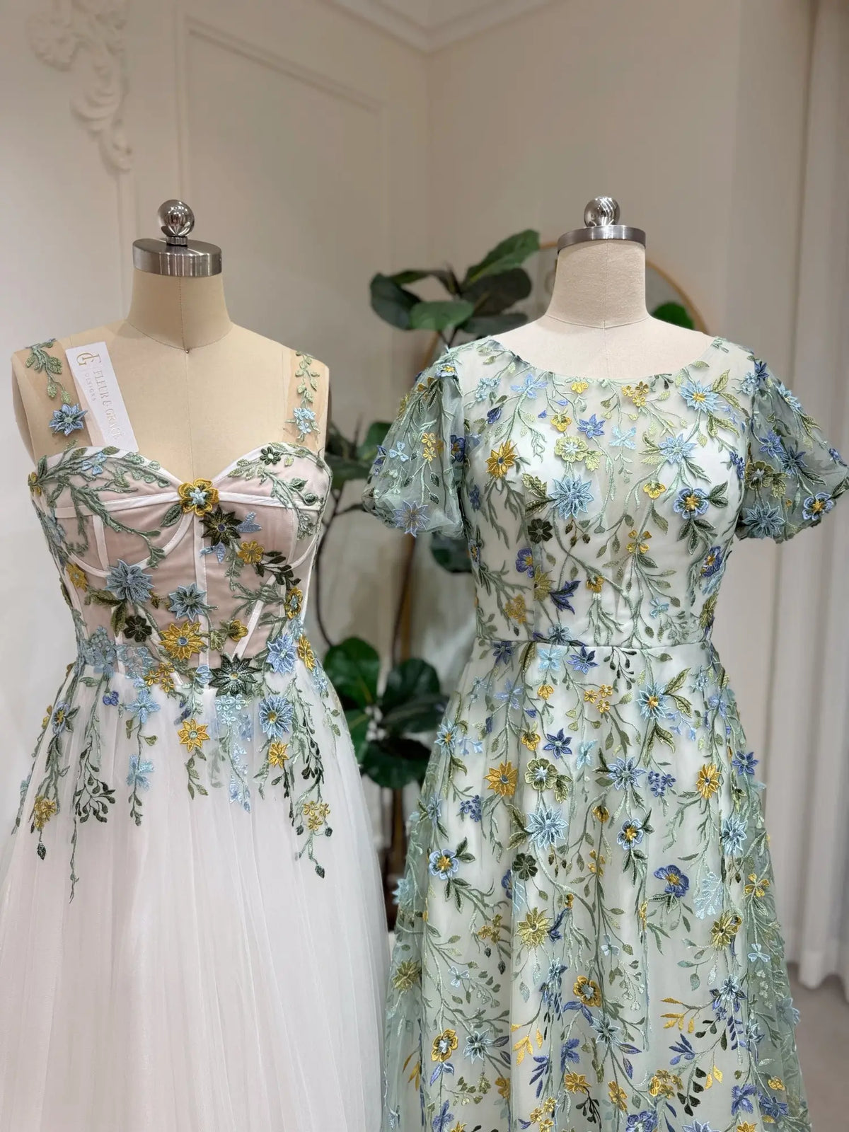 Meadow green tulle wedding gowns with intricate blue and yellow floral embroidery, puff sleeves, and A-line silhouettes.