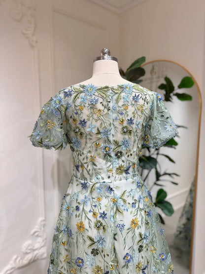 Meadow green tulle wedding dress featuring intricate blue and yellow floral embroidery and romantic puff sleeves.