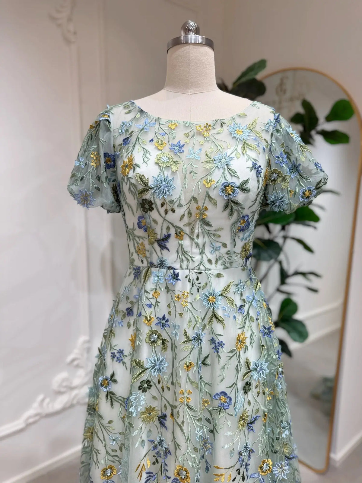 Meadow green tulle wedding dress with puff sleeves and intricate blue, yellow, and green floral embroidery.