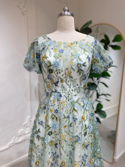 Meadow green tulle wedding dress with puff sleeves and intricate blue, yellow, and green floral embroidery.