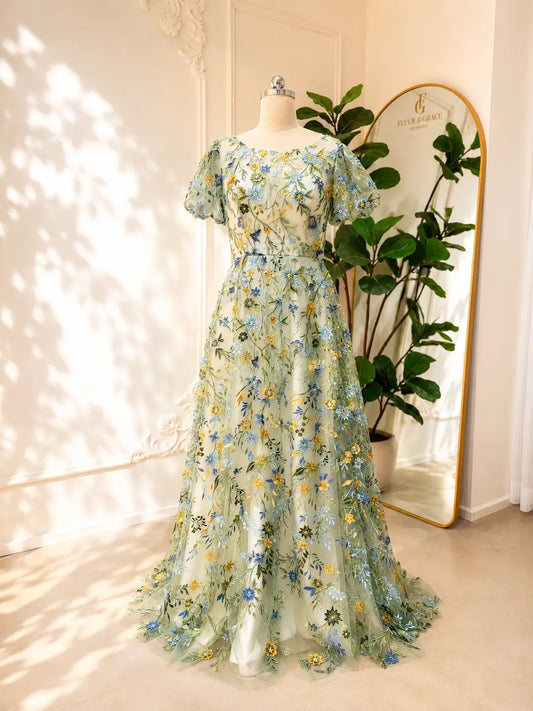 Meadow green tulle wedding gown featuring intricate blue and yellow floral embroidery, puff sleeves, and an A-line silhouette.