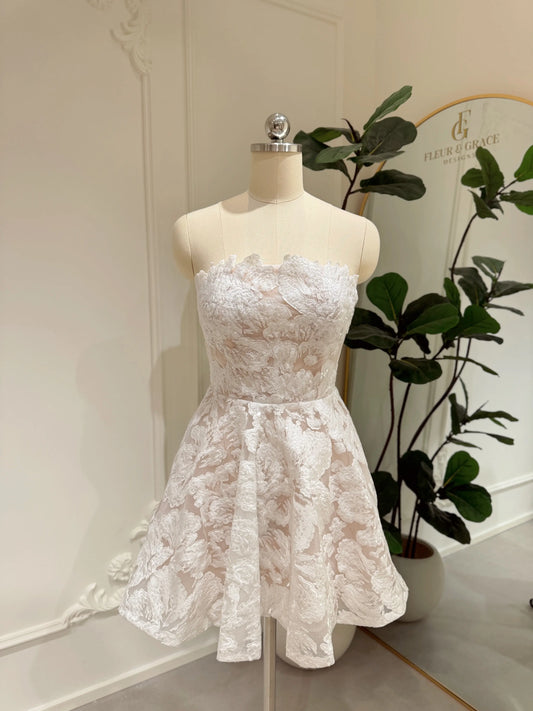 Strapless white floral embroidered mini dress with a corset bodice and A-line skirt on a mannequin.