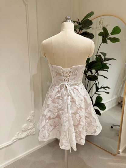 Strapless white floral embroidered mini dress with a corset bodice and lace-up back on a mannequin.