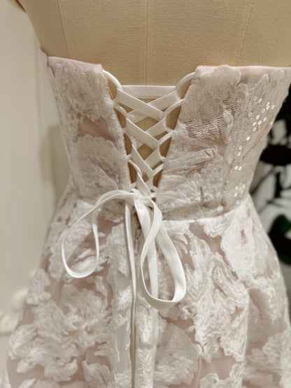 White strapless bridal mini dress featuring floral embroidered lace, shimmering sequins, and an adjustable lace-up corset back.