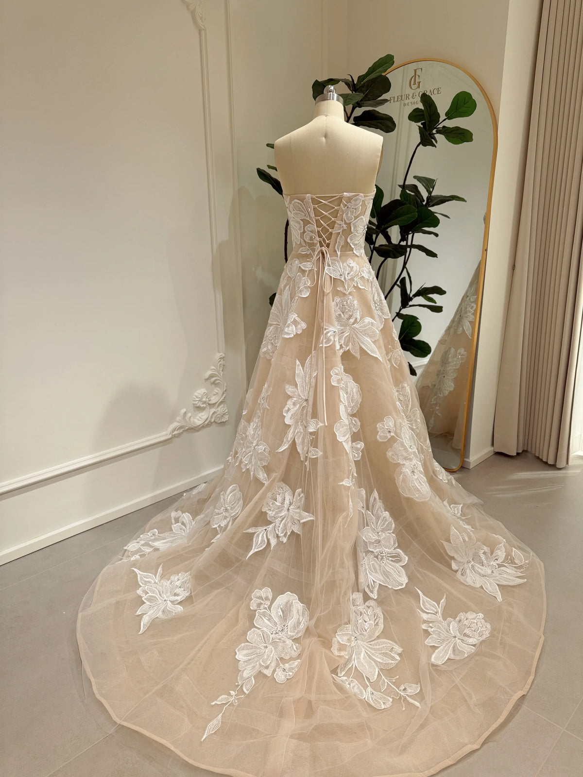 Strapless nude tulle wedding gown with ivory floral embroidery, rhinestone accents, and a lace-up corset back.