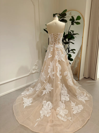 Strapless nude tulle wedding gown with ivory floral embroidery, rhinestone accents, and a lace-up corset back.