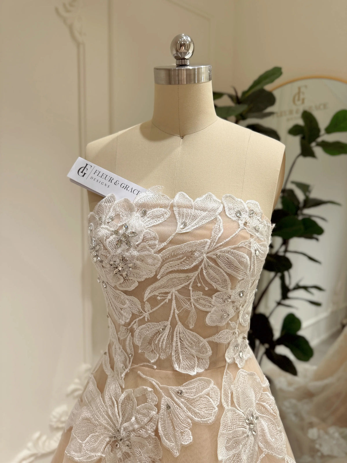 Strapless Mira wedding gown in nude tulle with ivory floral embroidery and handmade rhinestone embellishments.
