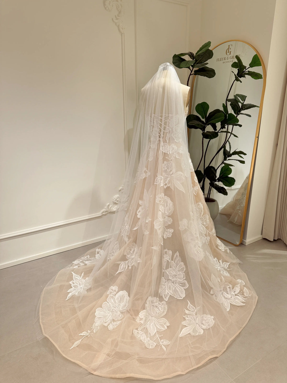 Strapless Mira gown in nude tulle with ivory floral embroidery, rhinestone accents, and a chapel-length train.