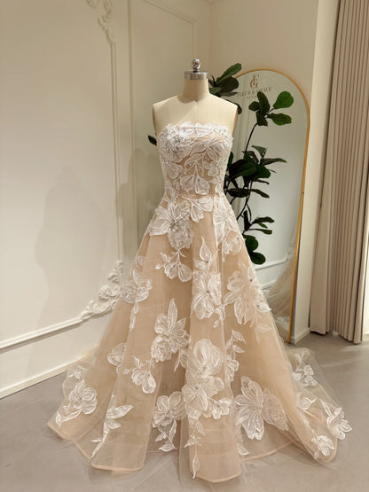 Strapless nude tulle wedding gown featuring white floral embroidery, rhinestone embellishments, and a chapel train.
