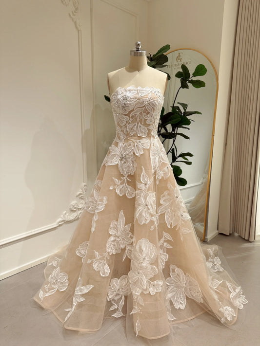 Strapless nude tulle wedding gown featuring white floral embroidery, rhinestone embellishments, and a chapel train.