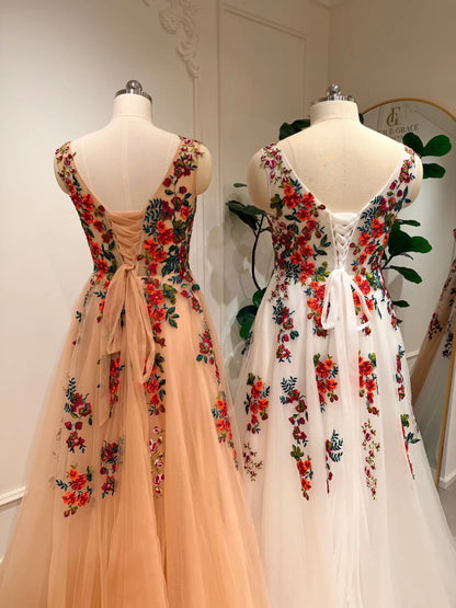 Two Monica A-line wedding dresses featuring vibrant floral embroidery, layered tulle skirts, and adjustable corset backs.