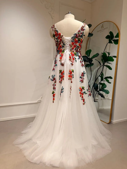 A-line wedding dress with vibrant floral embroidery on white tulle, featuring a romantic open back and lace-up corset closure.