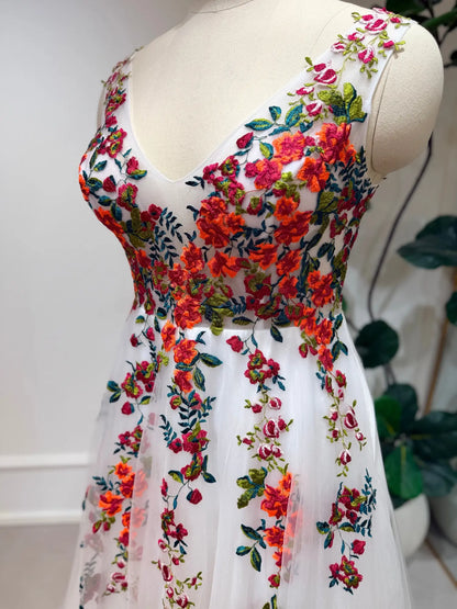 Romantic A-line wedding dress featuring vibrant floral embroidery on sheer tulle with a flattering structured bodice.