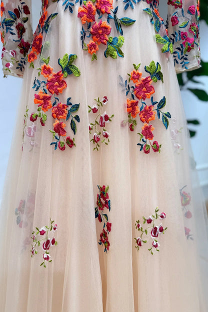 Champagne tulle wedding gown featuring vibrant orange floral embroidery and green vine details on an A-line silhouette.