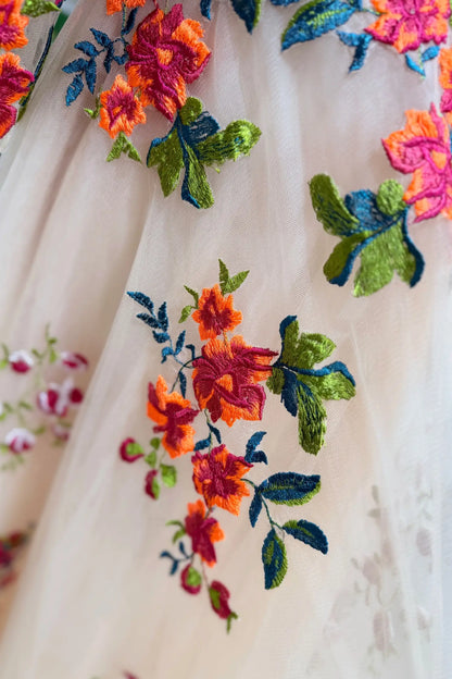 Champagne tulle wedding gown with vibrant orange, red, and green floral embroidery and delicate vine detailing.