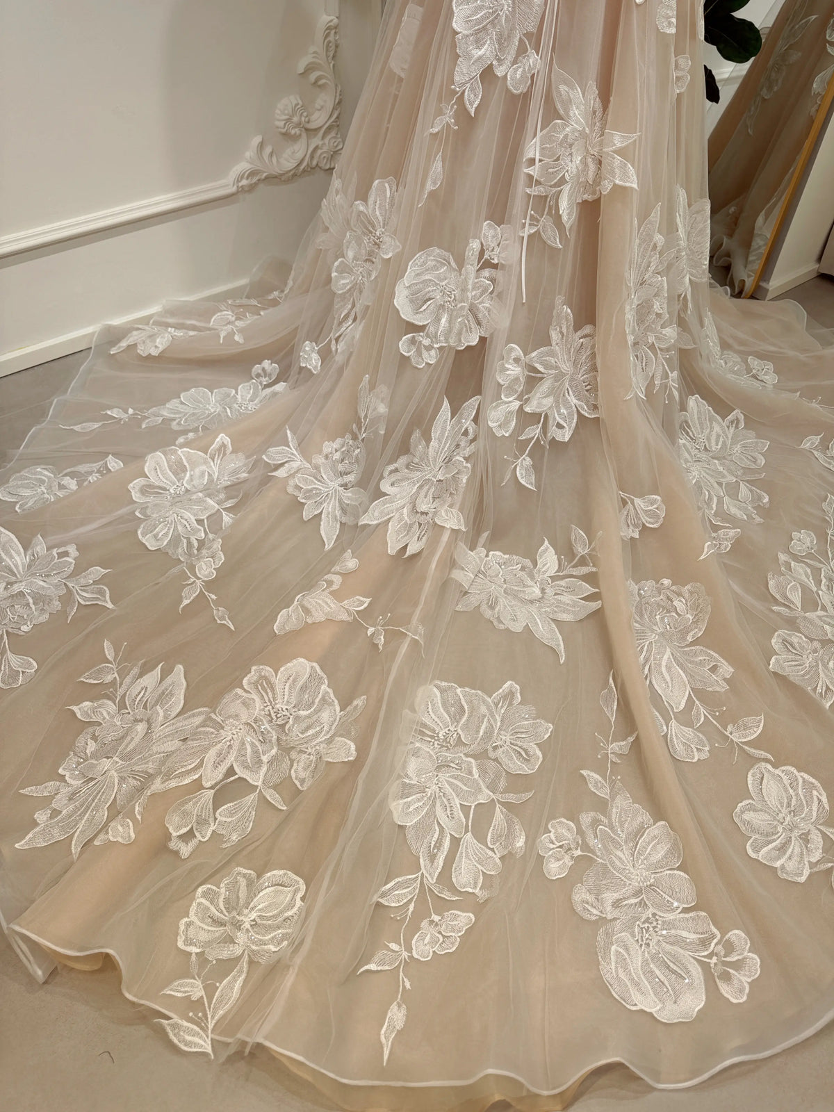 Nude tulle wedding dress skirt featuring intricate ivory floral embroidery and a dramatic cathedral train.