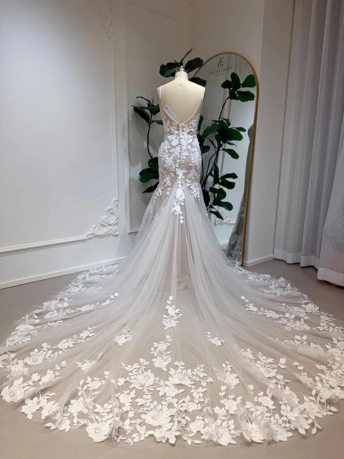 Nola mermaid wedding dress with floral lace appliqué, nude illusion lining, and a dramatic, flowing lace-trimmed train.