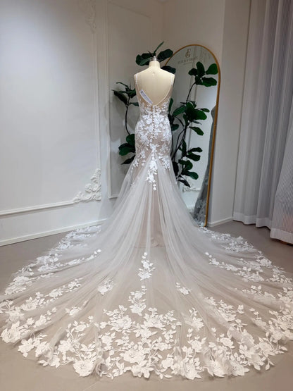 Nola mermaid wedding dress with floral lace appliqué, nude illusion lining, and a dramatic, flowing lace-trimmed train.