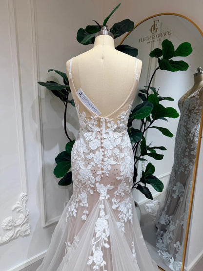 Back view of a mermaid wedding dress with floral lace appliqué, nude illusion lining, and delicate button-up back.