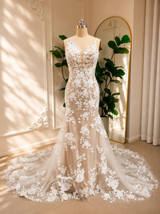 Nola mermaid wedding dress with white floral lace appliqué, nude illusion lining, and a graceful lace-trimmed train.