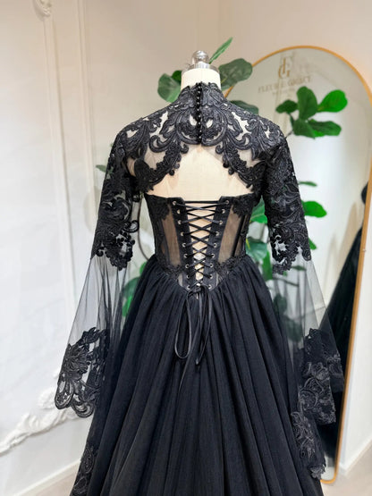 Black gothic wedding dress with intricate lace, sheer detachable sleeves, and a corset back on a mannequin.