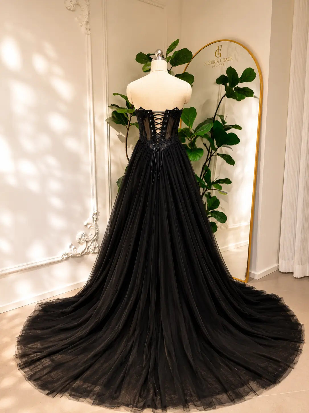 Black gothic wedding dress with a lace-up corset back, sheer bodice, and a voluminous A-line tulle skirt.