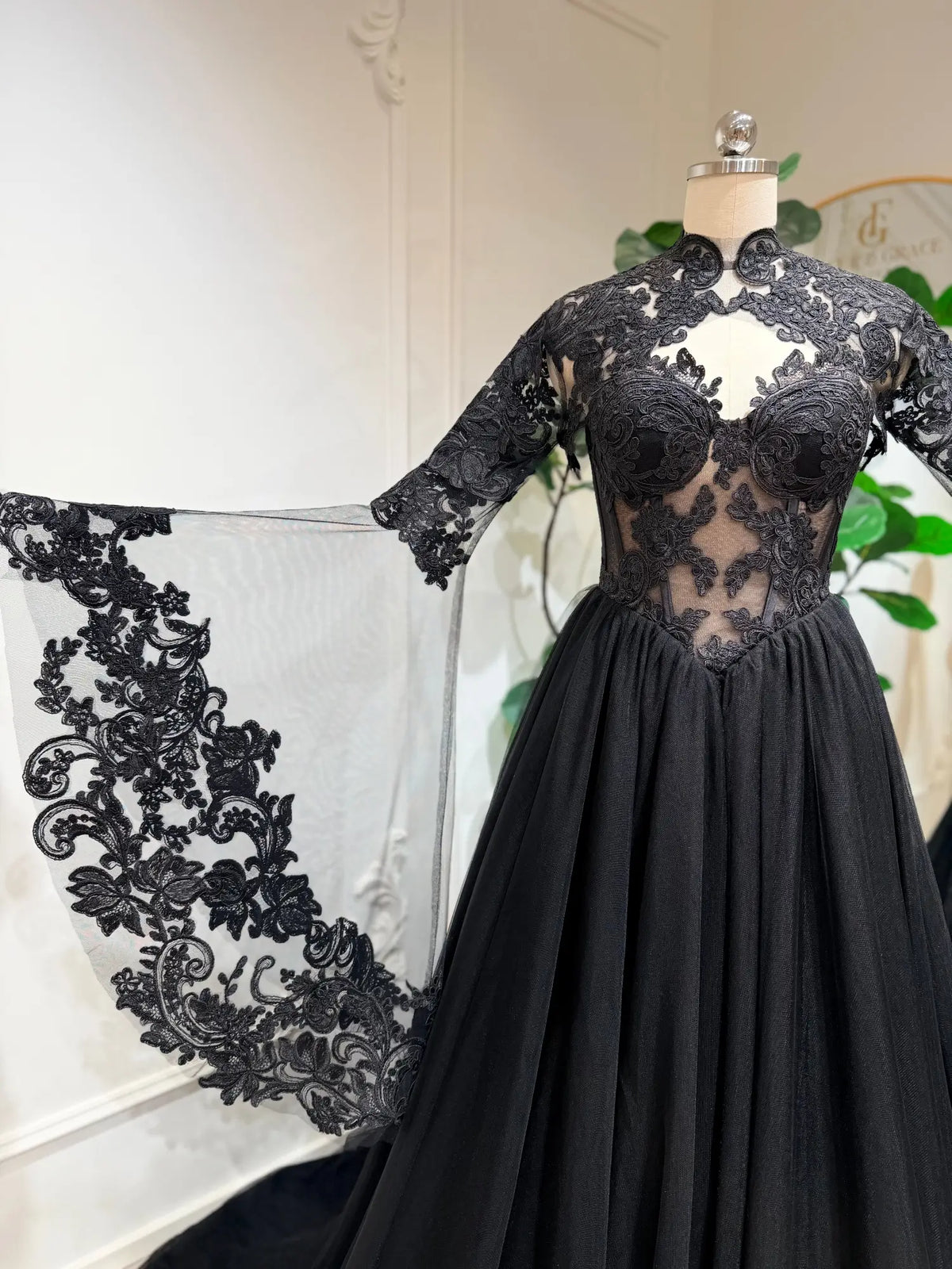 Black gothic wedding dress with intricate floral lace, sheer illusion bodice, and dramatic detachable lace sleeves.