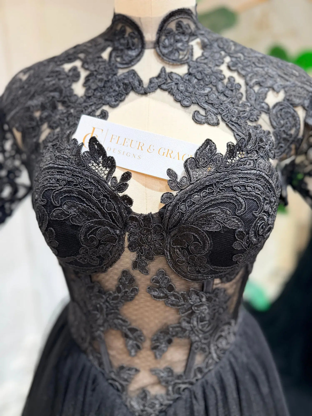 Black gothic wedding dress with intricate floral lace appliqué, structured corset bodice, and sheer illusion mesh.