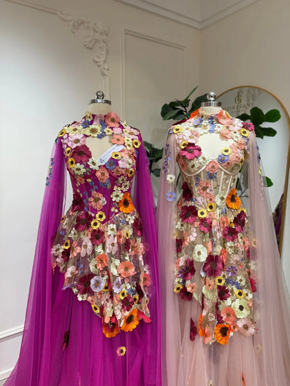 Magenta and blush tulle corset gowns featuring 3D floral appliqués and elegant detachable cape sleeves.