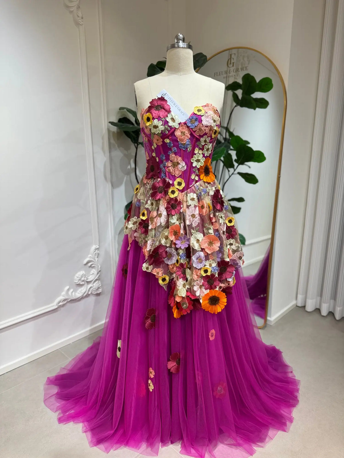 Magenta corset gown with 3D multicolor floral appliqués and a voluminous layered tulle A-line skirt.