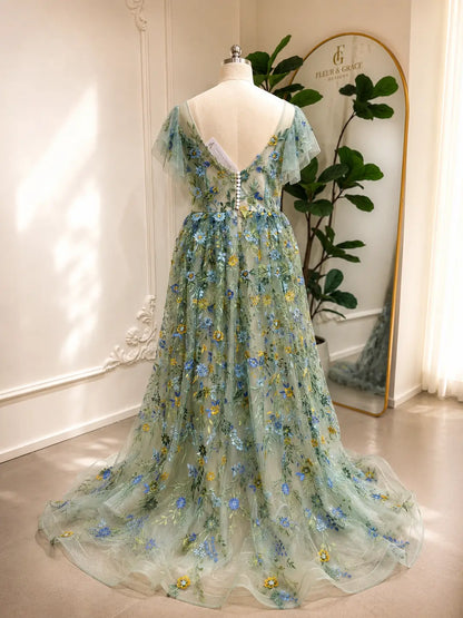 Sage green tulle gown with blue and yellow floral embroidery, angel sleeves, and a button-back corset bodice.