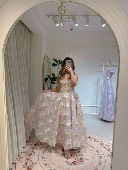 Woman wearing a pink ankle-length gown with 3D hydrangea floral lace and a sparkly bodice, reflected in an arch mirror.