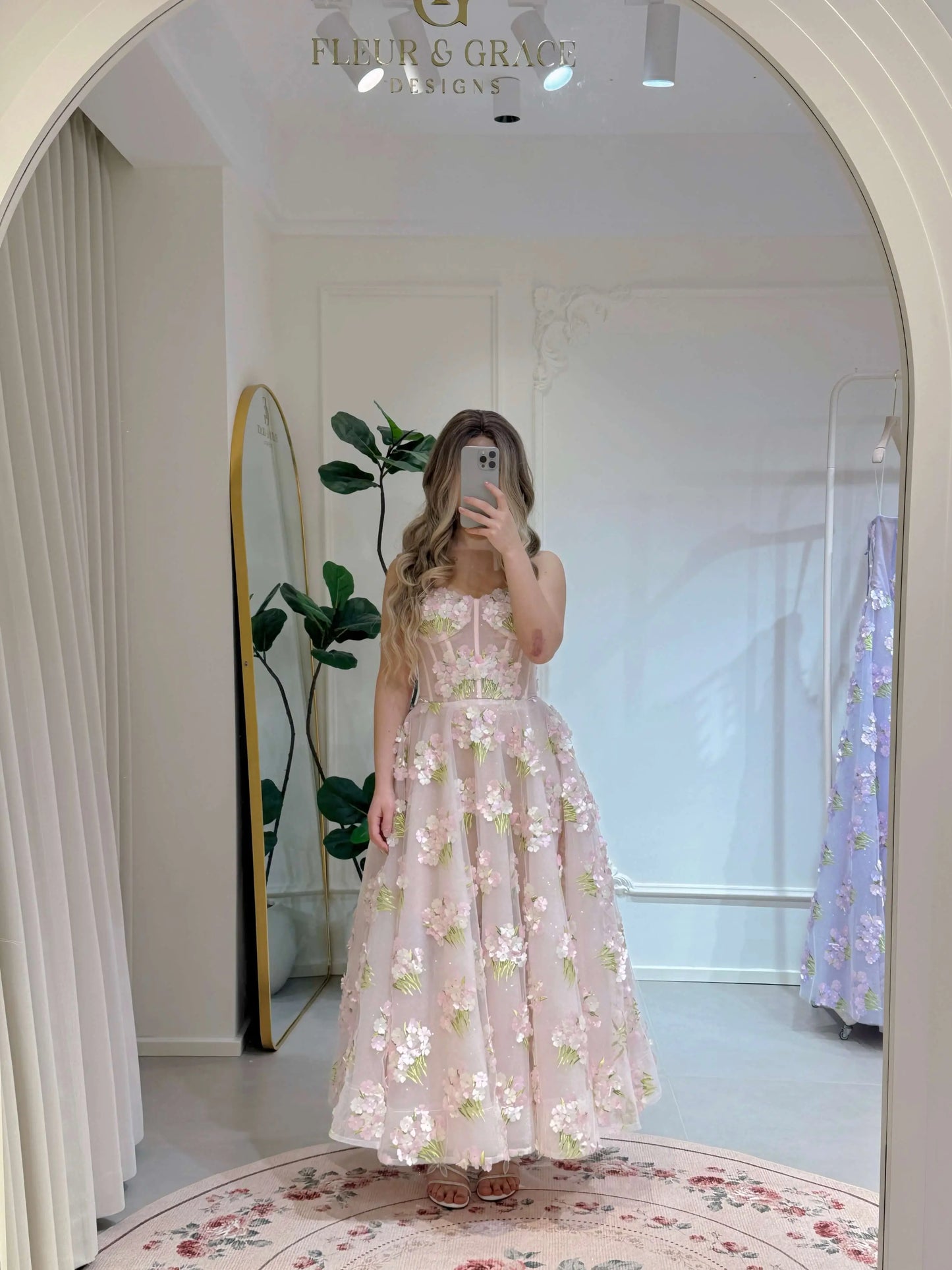 Pink ankle-length gown with 3D hydrangea floral lace, sparkly lining, and a structured bodice, reflected in a mirror.