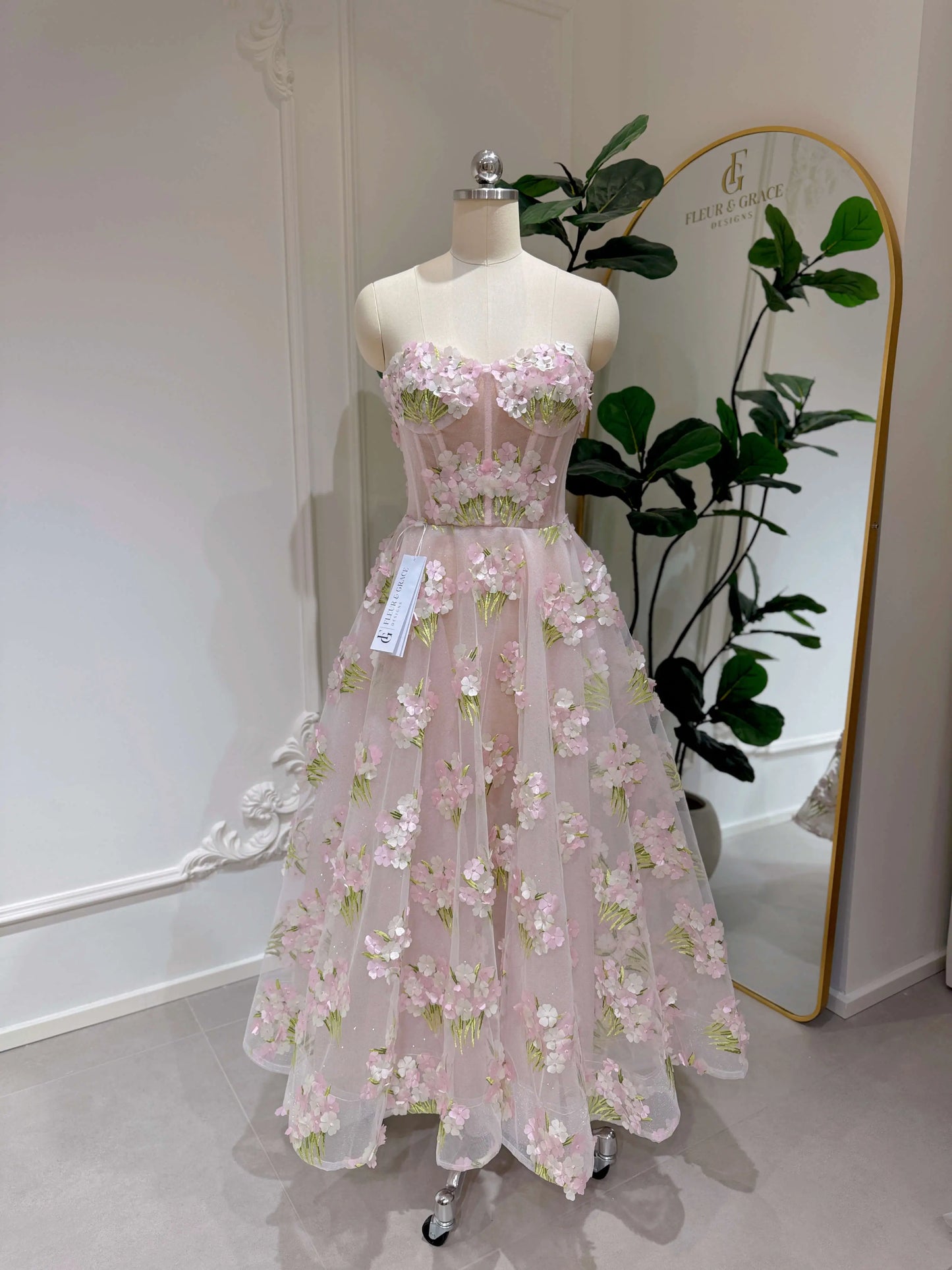 Pink ankle-length gown with 3D hydrangea floral lace, sparkly lining, and a structured bodice on a dress form.