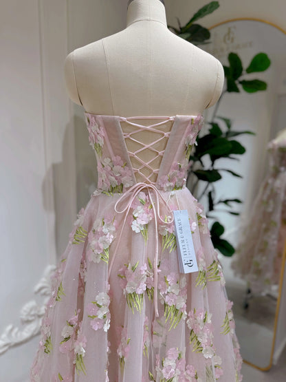 Pink ankle-length gown with 3D hydrangea floral lace, sparkly lining, and a corset-style lace-up back on a mannequin.