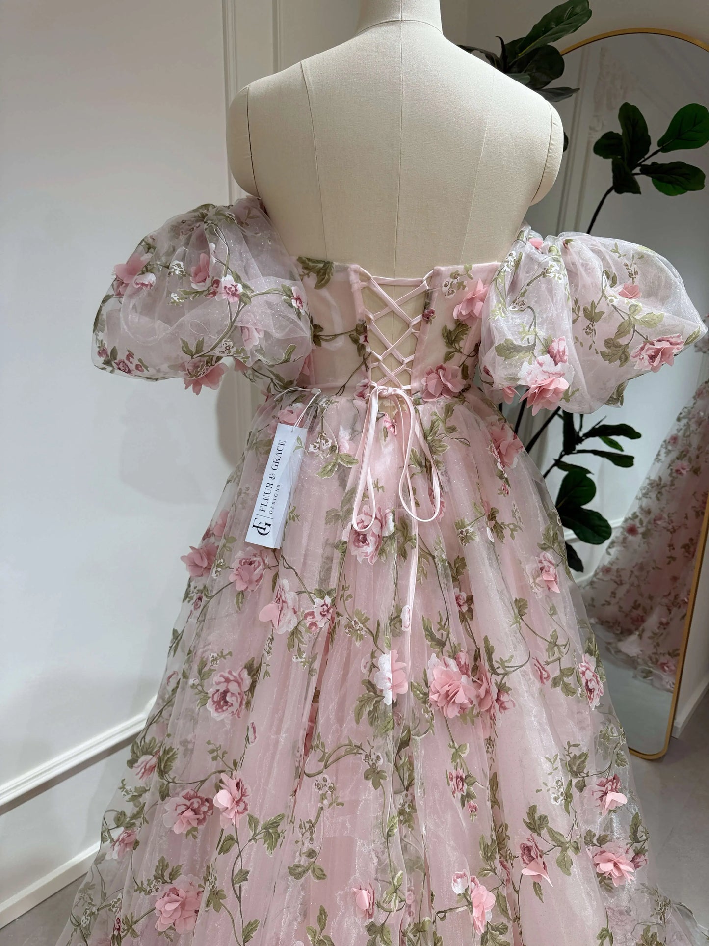 Pink 3D floral organza gown with removable puffy sleeves, sweetheart neckline, and adjustable lace-up back on a mannequin.