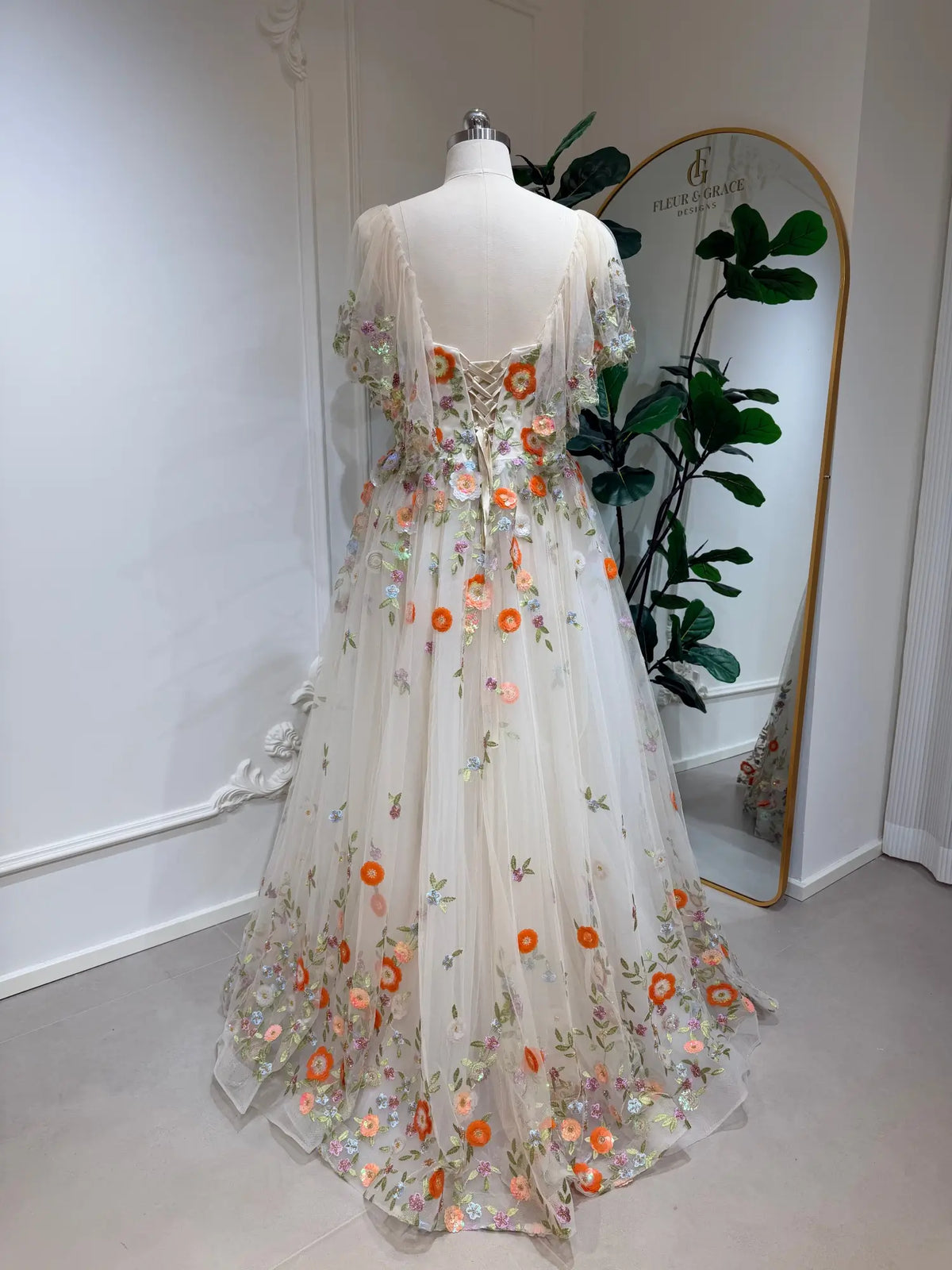 Raya floral embroidered tulle wedding dress with angel sleeves and corset back on a mannequin.
